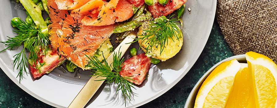 Två tallrikar med gravad lax som dekorerats med dill och citron. 